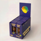 Ein Tray Cosmic Bites Energy Balls der Sorte Mango ist zu sehen, das sechs einzelne Packungen enthält. Die gelben Bälle sind dem Planeten Saturn nachempfunden, wonach die Sorte benannt ist. Der gesunde Snack besteht aus rein natürlichen Zutaten, ist vegan, hat keinen zugesetzten Zucker und einen stark reduzierten Dattelanteil von nur 25%.