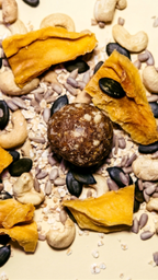 Cosmic Bites Energy Ball inspiriert vom Planet Saturn mit getrockneter Mango, Cashews und Kernen auf einem Bett aus natürlichen Zutaten – gesunder Snack mit wenig Datteln.
